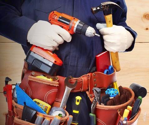 Profissional com furadeira, martelo e cinto de ferramentas para consertos e instalações